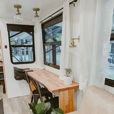 a living area with a table, chair and window in the back ground next to a couch