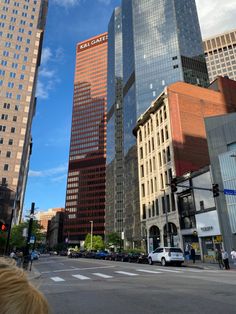 a city street filled with tall buildings under a blue cloudy sky and traffic lights at an intersection