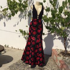 a mannequin dressed in a red and black floral print dress next to a tree