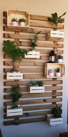 wooden pallet wall with planters and potted plants on it in front of a white wall