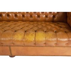 a brown leather couch with nail polishing on the armrests and foot rest