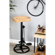 a bicycle mounted to the side of a wall next to a wooden table and stool