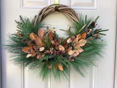 a wreath on the front door decorated with pine cones and leaves