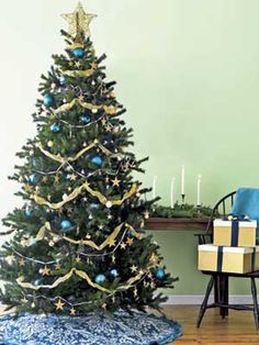 a small christmas tree with blue and gold ornaments on it in front of a fireplace