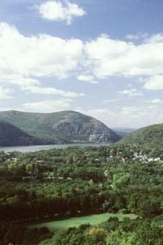 an aerial view of some hills and trees in the foreground with a body of water in the distance