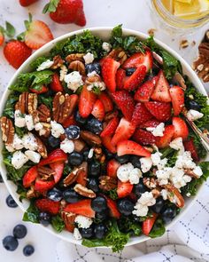 a salad with strawberries, blueberries, pecans and feta cheese