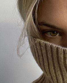 a close up of a person wearing a knitted scarf and looking at the camera