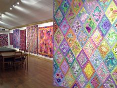 a room filled with lots of colorful quilts on display