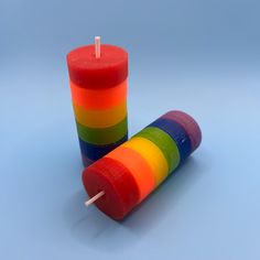 two colorful candles sitting next to each other on a blue surface with one candle in the middle