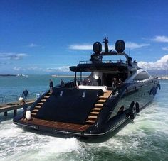 a large boat in the water with people standing on it's deck and looking out at the ocean