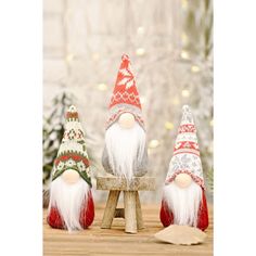 three christmas gnomes sitting on top of a wooden bench