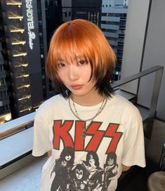 a woman with red hair and bangs standing in front of a window looking at the camera