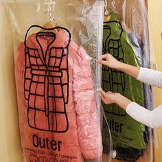 a woman standing next to a plastic bag with clothes hanging from it's sides