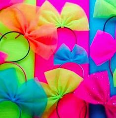 several different colored bows are arranged on colorful paper with black hair clips in the middle