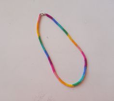 a multicolored necklace is displayed on a white surface