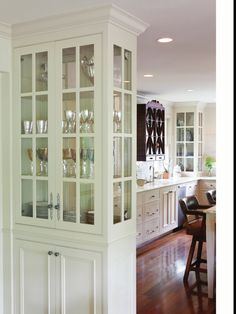 a white china cabinet with glass doors in a kitchen next to a dining room table