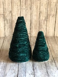 two small green christmas trees sitting on top of a wooden table next to each other