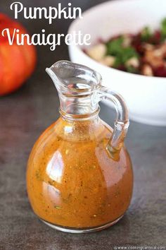 pumpkin vinaigrete in a glass carafe next to a bowl of salad