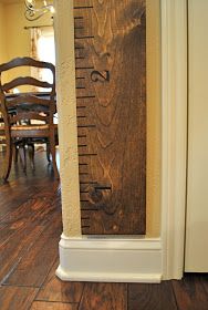 a tall wooden ruler sitting on top of a hard wood floor next to a dining room table