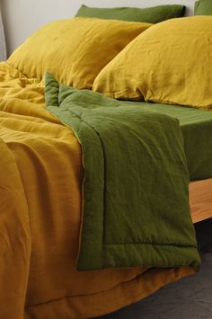 an unmade bed with yellow and green linens on the sheets, along with two pillows