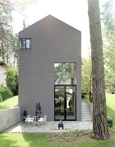 a small gray house sitting next to a tree