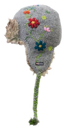 Part of the 2020 collection: The Reshma Earflap is a half faux fur-lined earflap. It combines the tassels of our classic earflap with the comfort and style of our fur hats. The reverse-knit base is topped with hand-embroider flowers down one side. The green embroidered stem meets the tassels of the hat and is braided in. The Reshma's Earflap also features a faux fur accent at the front. Like all of our wool products, the Reshma Earflap is: 100% New Zealand wool Hand-dyed Hand-knitted Unique to y Warm Faux Fur Hats With Ear Flaps, Winter Faux Fur Hats With Ear Flaps, Faux Fur Winter Hat With Ear Flaps, Winter Hats With Faux Fur Trim And Ear Flaps, Winter Hat With Feather Trim, Adjustable Winter Hat With Feather Trim, Floral Beanie, Wool Products, Fur Hats