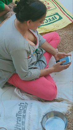 a woman sitting on the ground looking at her cell phone while she is cleaning it