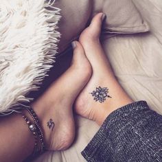 two people laying on top of a bed with their feet crossed and tattoos on them