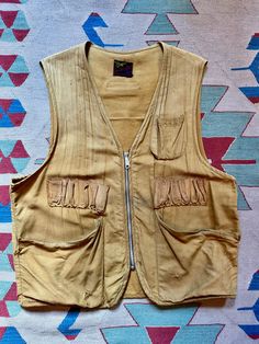 Up for grabs is a great vintage sportswear vest from the 1940s/1950's by "Sport-Bilt- Custom Built & Water-Repellant". Made of a golden brown cotton canvas material that is very worn in and has a nice patina. Large pockets at the hips and chest pockets for shotgun shells or fishing tools. Large silver metal YKK zipper down the front.  Measurements: OSFM 46" chest ptp 25" length Condition is fair. Wearable as is with a great look, but there are some small holes and marks and the pockets could be stitched back in place if desired. Being sold as-is. Please see pics and ask any questions prior to purchase as all sales are final. Price includes shipping in the USA! Thanks for looking! Retro Brown Cotton Vest, Vintage Outdoor Vest For Fall, Vintage Vest For Outdoor Fall Activities, Vintage Khaki Vest With Pockets, Retro Vest With Pockets, Vintage Khaki Vest For Outdoor, Vintage Cotton Vest Outerwear, Vintage Cotton Vest For Outdoor, Vintage Vest With Pockets