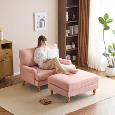 a woman sitting on a pink chair in front of a window