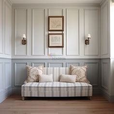 a couch sitting in the middle of a living room next to a wall with pictures on it