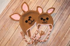 two crocheted hats with ears on top of wooden floor next to each other