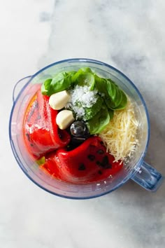 a blender filled with vegetables and cheese on top of a marble countertop next to a knife