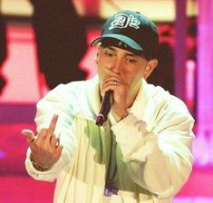 a man holding a microphone in his right hand and wearing a hat on top of his head