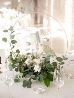 the table is set with white flowers and greenery for an elegant centerpiece on it