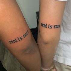 two people with tattoos that say real is not real