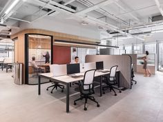 an office with two people working at desks and one person standing in the background