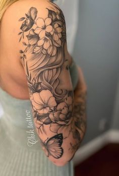 a woman with a butterfly and flowers tattoo on her arm