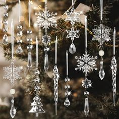 an assortment of christmas ornaments hanging from a tree with snowflakes and stars on it