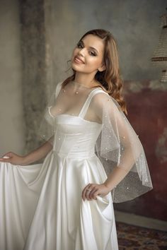 a woman in a white dress and veil posing for the camera with her hands on her hips