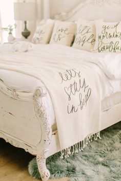 a white bed sitting on top of a hard wood floor next to a green rug