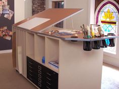 a room that has a desk with many items on it in front of a stained glass window