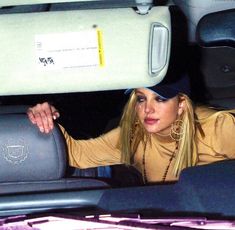 a woman is sitting in the back seat of a car with her hand on the backseat