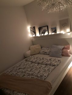 a bed with pillows and blankets on top of it next to a wall mounted light