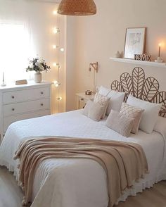 a bed with white sheets and pillows in a bedroom next to a window filled with lights