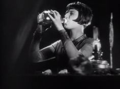 a woman drinking from a glass in the dark