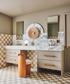 a bathroom with checkered flooring and marble counter tops, two sinks and mirrors on the wall