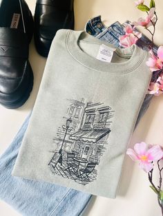 a t - shirt with a drawing on it sitting next to some shoes and flowers