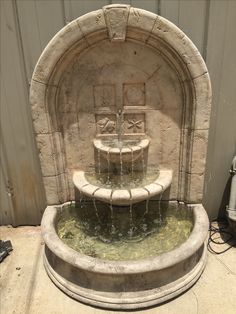 a stone fountain with two benches in the center and water coming out from it's sides