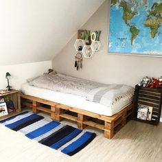 a bed made out of wooden pallets in a room with a map on the wall